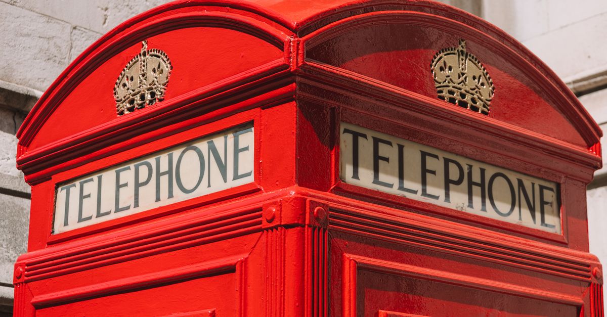 Classic red telephone booth on a street in London, England, symbolizing British tradition.