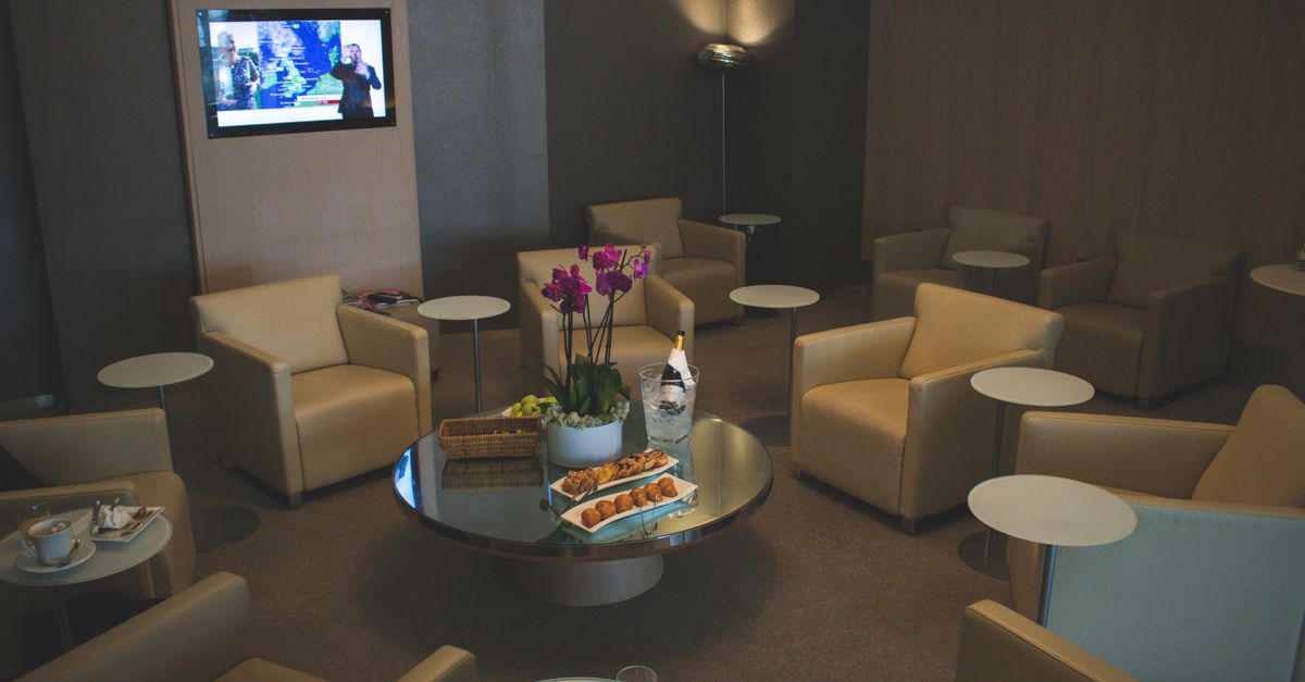Comfortable armchairs and a coffee table with snacks and champagne in an airport lounge