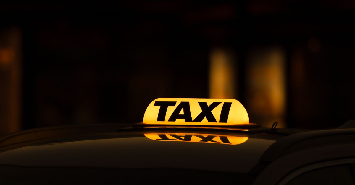 Illuminated 'TAXI' roof-light sign glowing amber against a dark background