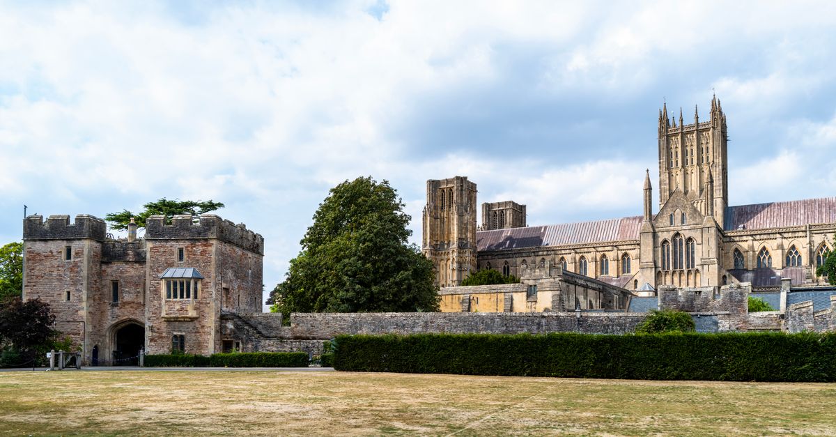 Wells Cathedral and Bishop's Palace gatehouse in Somerset under a partly cloudy sky