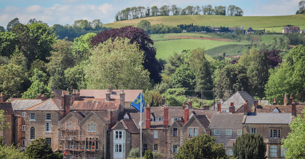 Rooftops of a stone-built English market town beneath rolling green hills