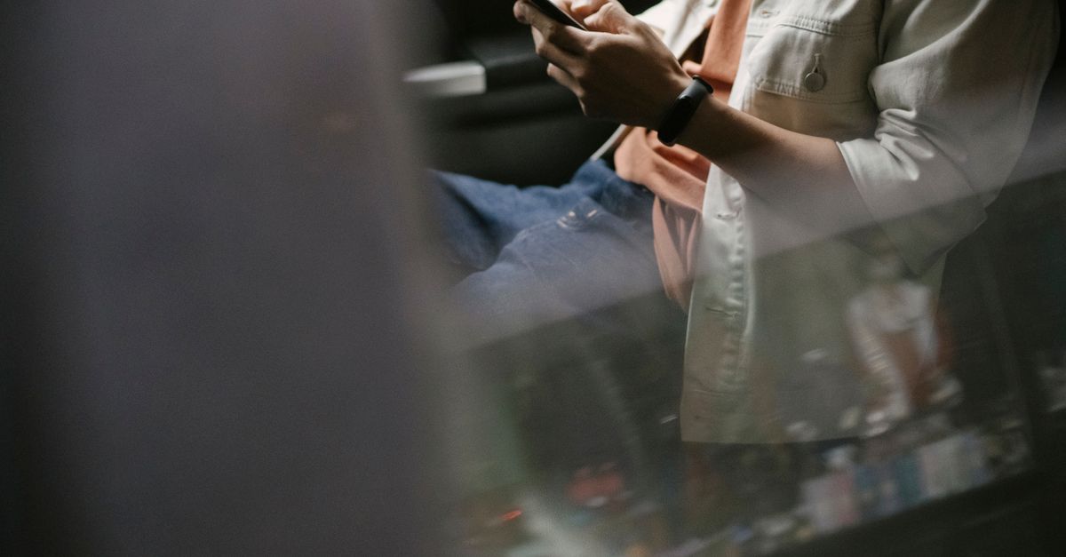 Passenger in the back of a car checking their phone screen
