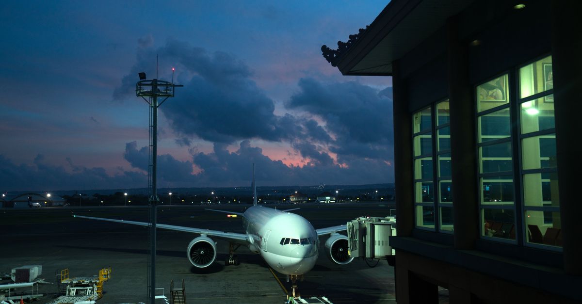 Contemporary aircraft located near airbridge on modern airport airfield against scenic dusk sky